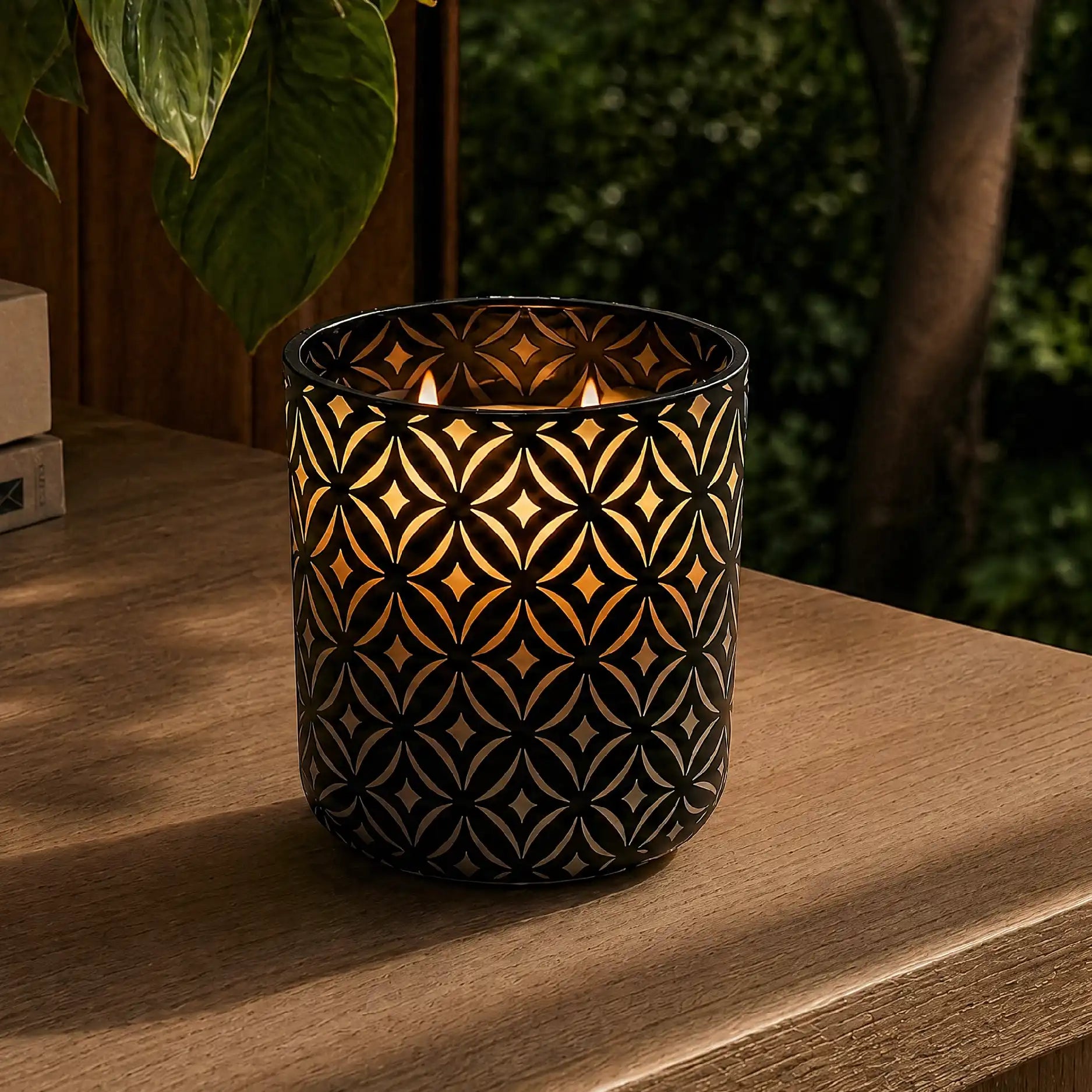 Custom etched candle glowing outdoors with curve design in black